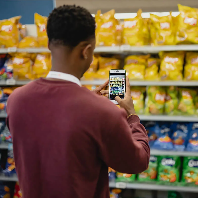 Shopper photographing a snack aisle on a store shelf